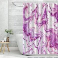 a white bath tub sitting next to a shower curtain with purple swirls on it