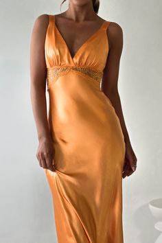 a woman in an orange dress posing for the camera