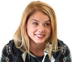 a woman holding a toothbrush in her hand and smiling at the camera while looking into the camera