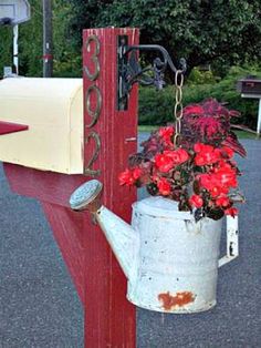 a red post with a watering can and flowers on it