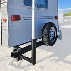 an rv parked in the sand with its door open and wheels on it's side