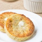 two pieces of bread on a plate next to a cup and saucer in the background