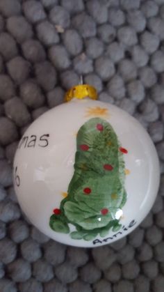 a white ornament with a green christmas tree painted on it's side