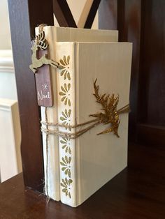 a white book with gold decorations tied to it on a wooden table next to a door