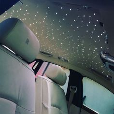 the interior of a car with stars on the ceiling and lights in the back seat