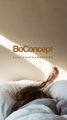 a woman laying on top of a bed under a white comforter with the word booconcept above her head