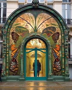 a man standing in front of an ornate doorway with butterflies painted on the doors and windows