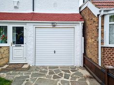 a white garage door in front of a brick house