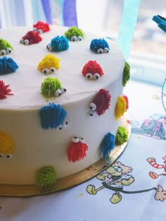 a cake decorated with colorful frosting and small monsters on it's sides, sitting on a table