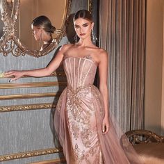 a woman standing in front of a mirror wearing a pink gown