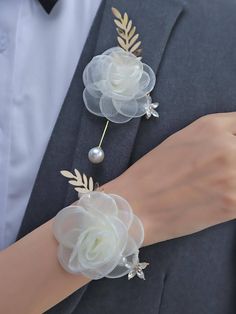 a man in a tuxedo with two flowers on his arm and a pearl beaded bracelet