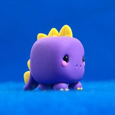 a purple toy with yellow spikes on it's head sitting on a blue surface