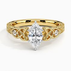 a yellow gold engagement ring with a pear shaped diamond in the center and an intricate band