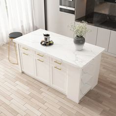 a kitchen island with white marble top and gold handles, in front of a stove