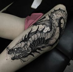 a woman's leg with a black and white dragon tattoo on her thigh,