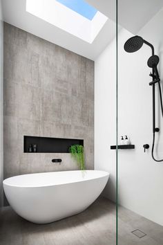 a bathroom with a large white bathtub next to a shower head and wall mounted faucet