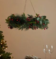 a christmas wreath hanging from the ceiling over a table with wine glasses and napkins