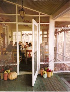 people are sitting at the table outside in front of an open porch with lots of windows