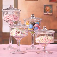 there are many different types of candies in the glass containers on the table together