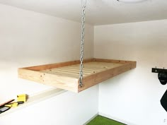 a bed suspended from the ceiling in a room with green carpeting and white walls