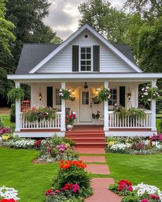 a white house with flowers in the front yard and steps leading up to the front door