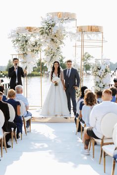 a bride and groom are walking down the aisle at their wedding ceremony by the water