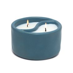 two tea lights sitting in a blue bowl on a white surface with one candle lit