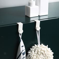 two white towels hanging from hooks on a green cabinet