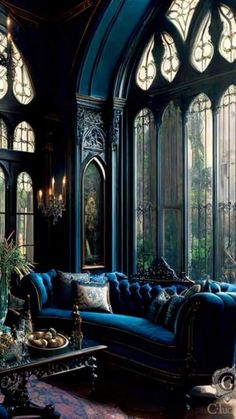 a living room filled with blue couches next to tall arched windows and chandeliers