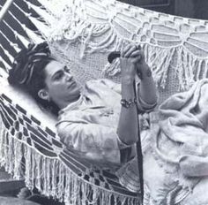 a woman laying in a hammock with her feet propped up on the ground