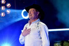 a man in white shirt and black hat on stage