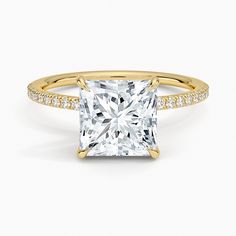 a princess cut diamond ring with pave set diamonds on the shoulders and sides, in yellow gold