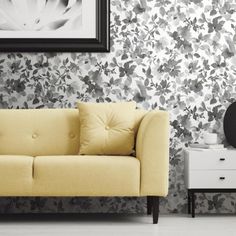 a living room scene with focus on the couch and wallpapered walls behind it