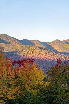 the mountains are covered in fall foliage and trees with orange, yellow, and green leaves