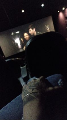 someone watching a movie in the dark with their feet on the chair and arm up