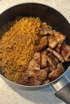 some noodles and meat are in a pan on the counter top, ready to be cooked