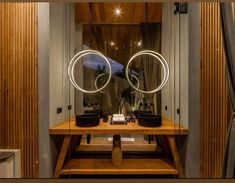 a bathroom with two round mirrors on top of a wooden table next to a window