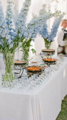 a table topped with lots of food and vases filled with flowers on top of it