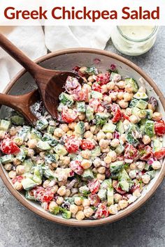 greek chickpea salad in a bowl with a wooden spoon and glass of milk