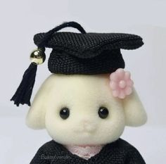 a stuffed animal wearing a graduation cap and gown with a bell on it's head