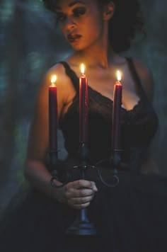 a woman holding three candles in her hands