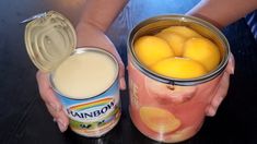 two hands holding a can of peaches and a glass of milk on a table