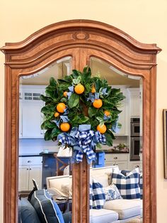 a mirror with a wreath on top of it in front of a couch and table