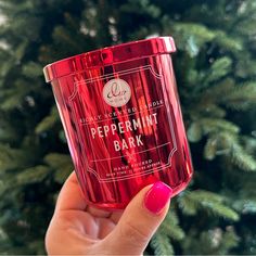 a woman holding up a red cup with peppermint bark on it in front of a christmas tree