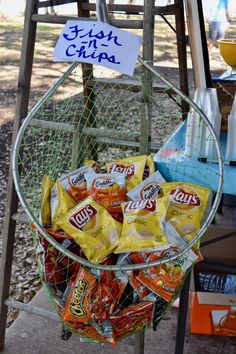 a basket filled with chips sitting on top of a wooden table next to a sign