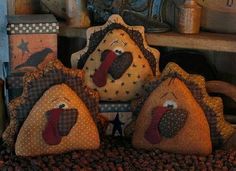 three stuffed turkeys sitting on top of a pile of coffee beans in front of a wooden shelf