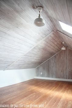 an empty room with wood flooring and skylights in the ceiling is seen here