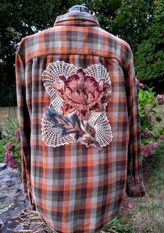 an orange and black plaid shirt with floral appliqued on the chest pocket