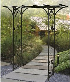 an iron garden arbor in the middle of a walkway