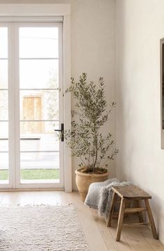 a living room with white walls and wooden flooring next to a large glass door